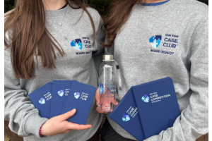Twee meiden die bedrukte notitieboekjes en een bedrukte fles vasthouden en een sweater met logo aan hebben.