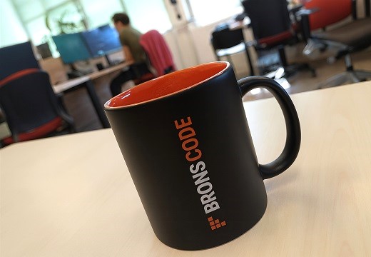 zwarte mok met oranje binnenkant met bronscode logo erop