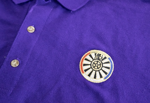paarse polo met een geborduurd logo erop
